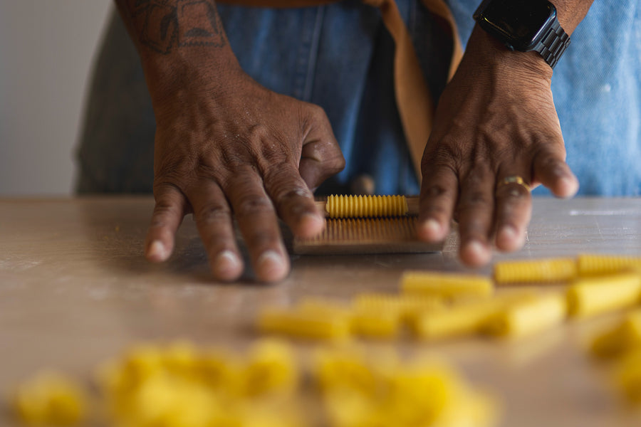 Rolling fresh pasta by hand on a wooden table