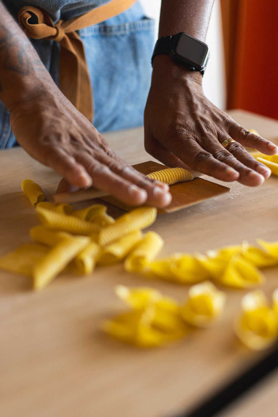 Shaping fresh pasta by hand on a wooden board at Pasta Packs